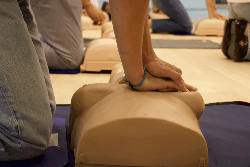Een persoon die reanimatie (borstcompressies) uitvoert op een oefenpop met borsten tijdens een training.